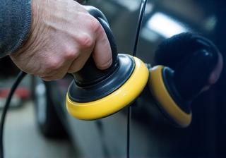Detailer carefully polishing a car panel to remove imperfections